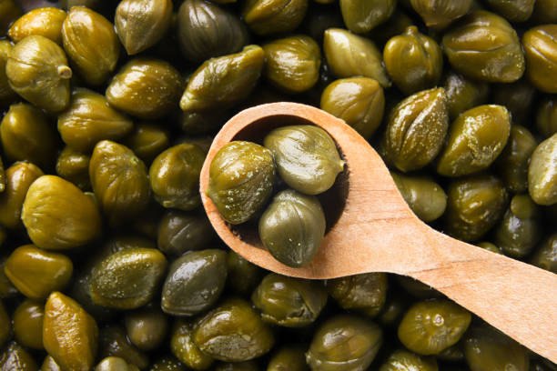istock Capers in a wooden spoon, background. Top view 1477512609