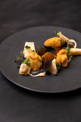 Fried schnitzel meat dumplings with parsnip vegetable and truffle gravy at gourmet Michelin food restaurant