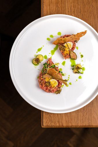 Gourmet food Beef Tartare with egg, herbs, capers, chives and truffle cream in elegant restaurant