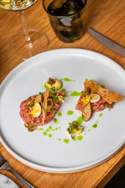 Gourmet food Beef Tartare with egg, herbs, capers, chives and truffle cream in elegant restaurant