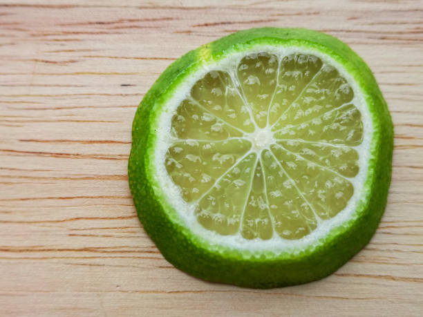 istock Green lemon slice on a light wooden plate. 1477515407