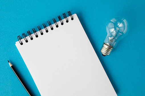 Notepad and light bulb on blue.