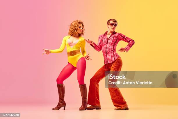 Young Stylish Emotional Man And Woman Professional Dancers In Retro Style Clothes Dancing Disco Dance Over Pinkyellow Background 1970s 1980s Fashion Music Concept Stock Photo - Download Image Now