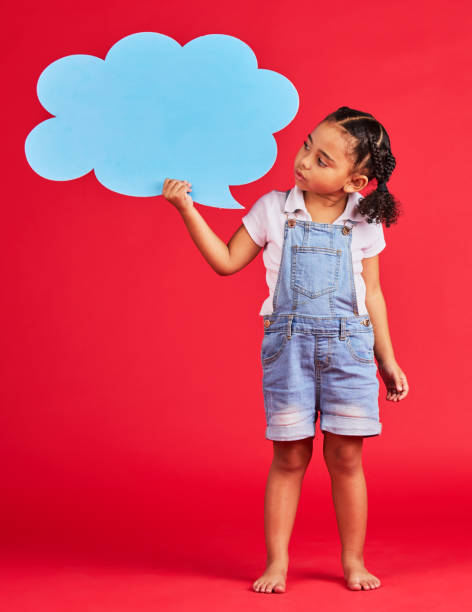istock Child, talking or speech bubble for ideas, opinion or vote on isolated red background for social media, vision or news. Thinking, kid or girl with banner, paper or cardboard poster for speaker mockup 1477518251