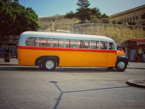 A Maltese bus speeding along, background blurred with the movement.