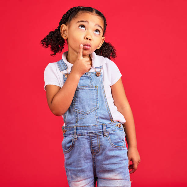 istock Kid, face or thinking finger on chin by isolated red background in games innovation, question or planning vision. Little girl, ideas or curious expression for child fashion clothes or curly hairstyle 1477520368