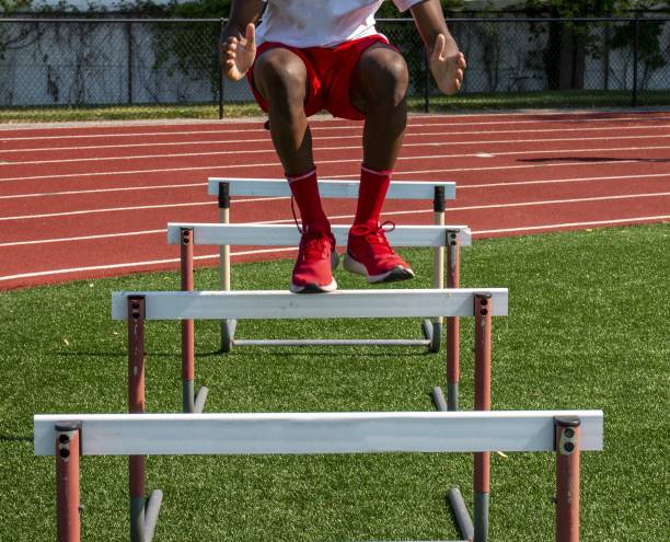 istock High school boy jumping over track hurdles for strength and flexibility 1477521522