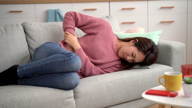 Young Woman Having Period Cramps At Home