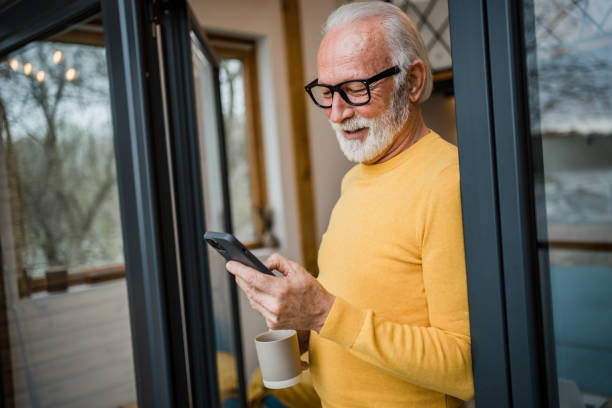 A gray-haired elderly man enjoys his morning coffee on the terrace