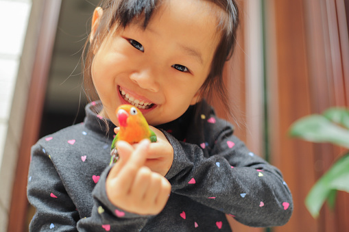 an Asian girl is playing with a little bird in a garden.