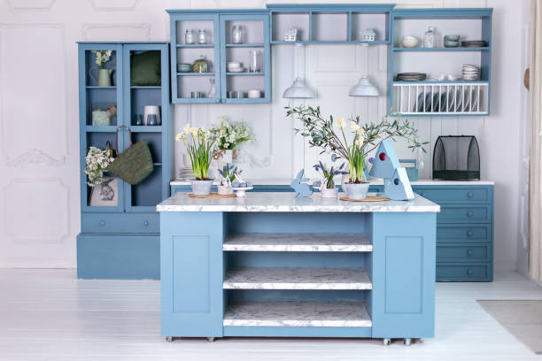 istock Wooden kitchen in easter decor. Cozy home decor. Kitchen utensils, dishes and plate on table. kitchen island in dining room. Blue kitchen interior with furniture. Stylish cuisine with flowers in vase. 1477526127