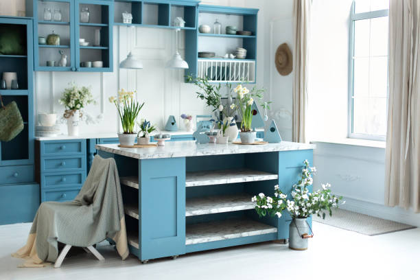 Wooden kitchen in easter decor. Cozy home decor. Kitchen utensils, dishes and plate on table. kitchen island in dining room. Blue kitchen interior with furniture. Stylish cuisine with flowers in vase.