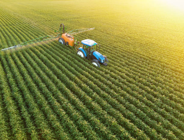 luftaufnahme einer pflanzenschutzspritze, die bei sonnenuntergang pestizide auf einem sojabohnenfeld versprüht - green crop tractor planting stock-fotos und bilder