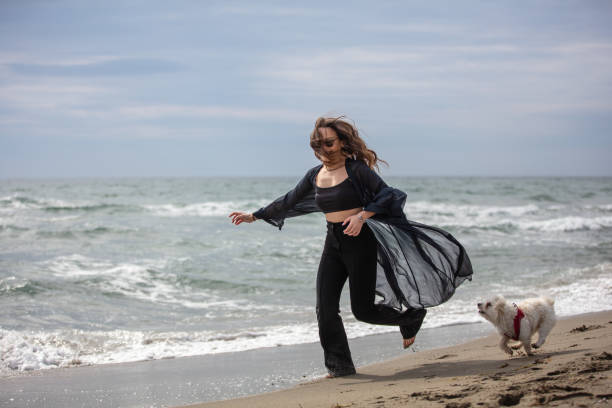 istock Young lady is running with her dog on the beach. 1477528822