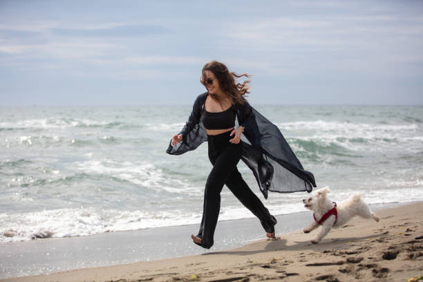 istock Young lady is running with her dog on the beach. 1477528957