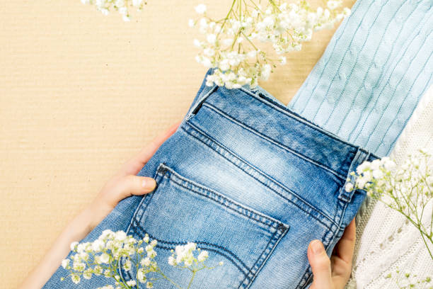 istock Female hands holding jeans near sweaters on cardboard background 1477530924