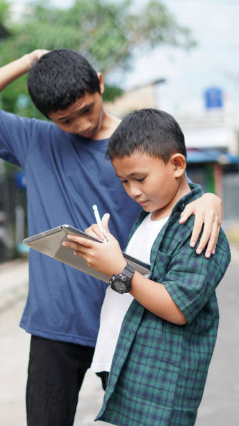 istock asian boy and brother using tablet phone in outdoor 1477537190