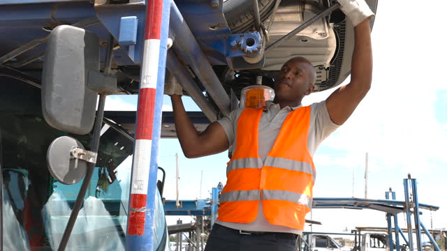 Black worker adjusting the safety straps of a vehicle on carrier ready for export