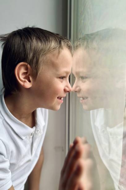 istock a boy in a white shirt looks out the window 1477539963