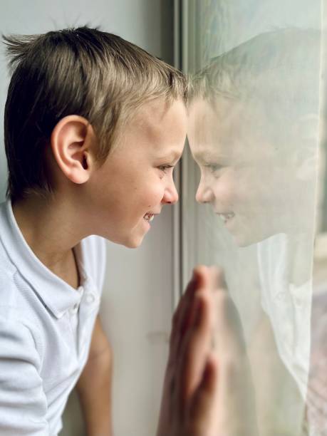 istock a boy in a white shirt looks out the window 1477539987