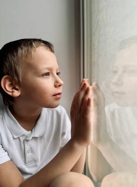 istock a boy in a white shirt looks out the window 1477540036