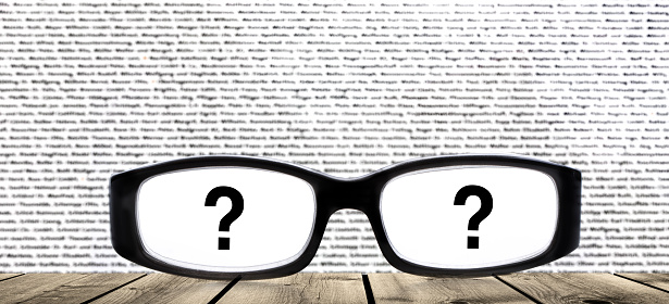 Glasses with question mark against blurred text background