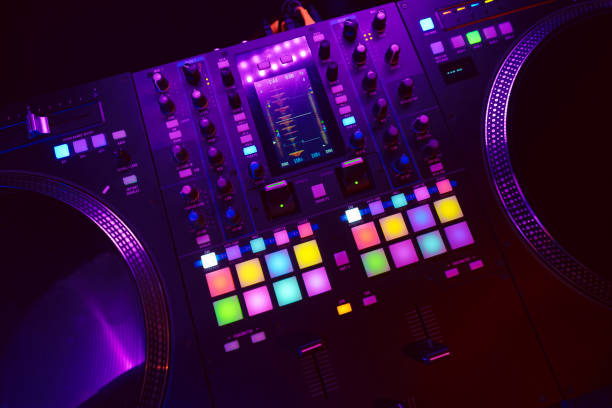 istock Close up of DJ mixing console in party light 1477540617