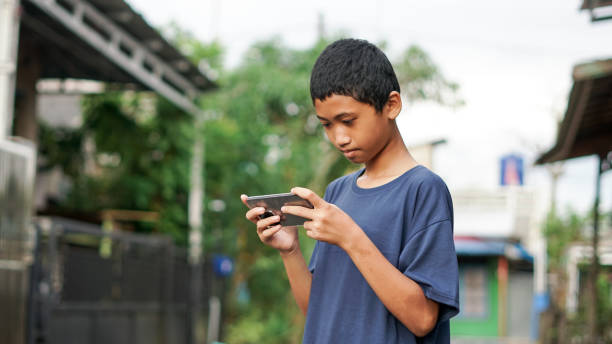 istock asian boy using smartphone in outdoor 1477543118