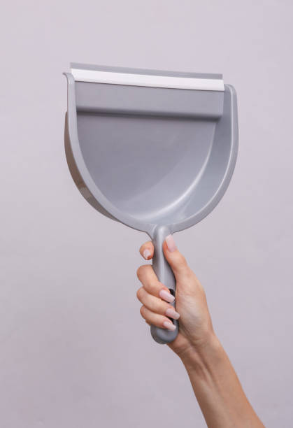 istock Woman's hand holds a scoop on a gray background. Cleaning concept 1477543221