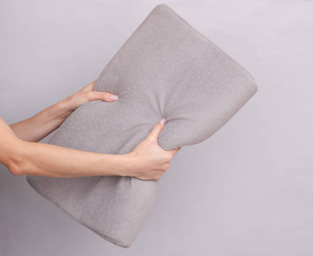 istock Female hands holding an orthopedic pillow on a gray background 1477543378