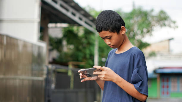 istock asian boy using smartphone in outdoor 1477544742