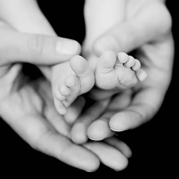 Feet of a newborn in the hands of her mother