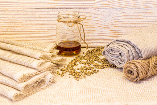 a rolled piece of natural hemp or linen fabric, rope, hemp seeds and oil