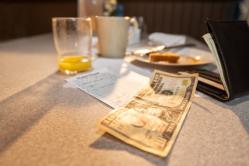 A $10 bill to pay for the sunrise breakfast of orange juice, toasted bread and a steaming hot cup of coffee in a diner.
