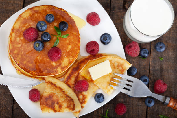 American pancakes with fresh blueberry, raspberry and honey served on white plate stock photo