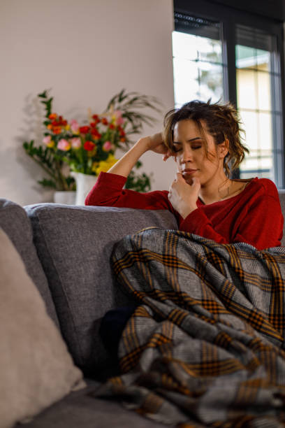 istock Young woman sitting on the sofa, under a blanket, struggling with negative emotions 1477556816