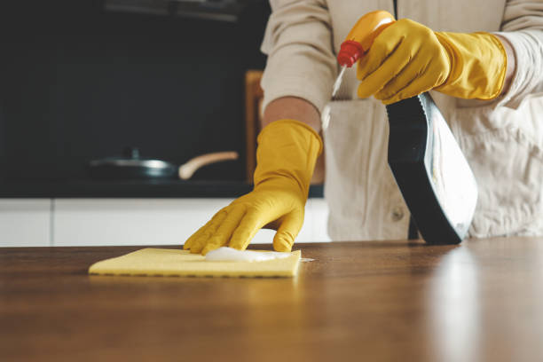 istock Closeup on woman's hands in yellow protective rubber gloves cleaning kitchen cabinets with sponge. 1477560846