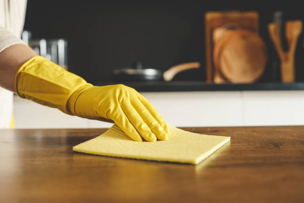 istock Closeup on woman's hands in yellow protective rubber gloves cleaning kitchen cabinets with sponge. 1477560907