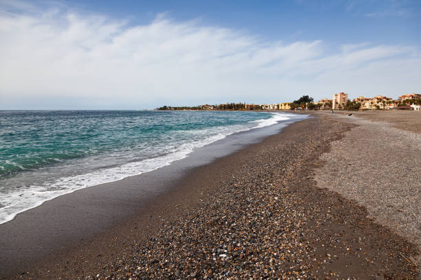 praia do mar espanhol na cidade de motril com água clara e uma pequena praia de seixos. - high tide - fotografias e filmes do acervo