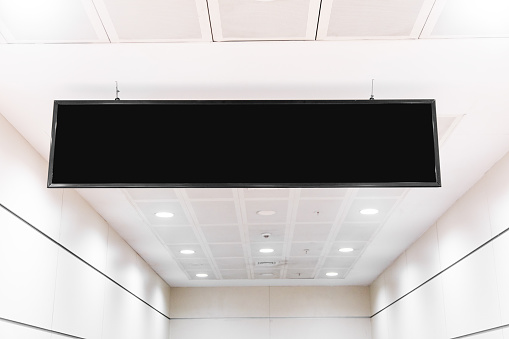 black blank signboard hanging from the ceiling. Black sign hanging from the white ceiling. mock-up