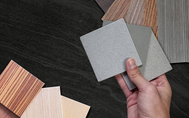 istock architect's hand holding grainy stone tile samples matching with many wooden samples material for interior renovation including wooden veneer and laminated on dark black stone for design. 1477564014