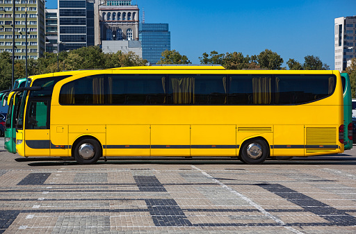 Modern yellow bus on city street at summer season side view
