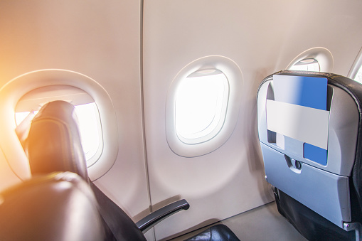 airplane seats and window. A photo taken from inside the plane. Unbranded. Passenger seats and window visible.
