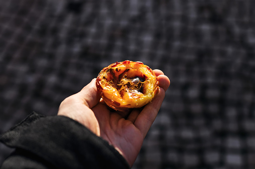 A close-up of the Portuguese dessert in the tourist's hand