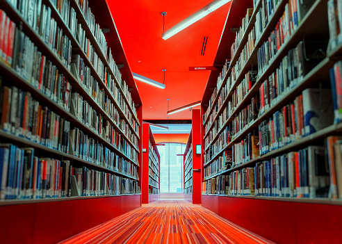 Boston, Massachusetts, USA - March 20, 2023: View down long aisle of library book shelves in the Boston Public Library in Boston's Back Bay neighborhood. Selective focus.