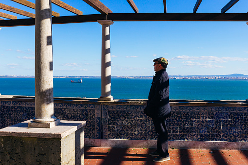 Lisbon, Portugal - Jan 28, 2018 The original observation deck is lined with porcelain ceramic tiles. A lonely man admires the beautiful view of the city and the river