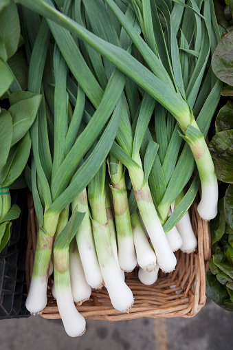 A basket of fresh leeks for sale at a farmer's market.