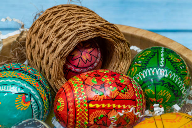 Color easter eggs in light wooden bowl on blue old wooden dirty table