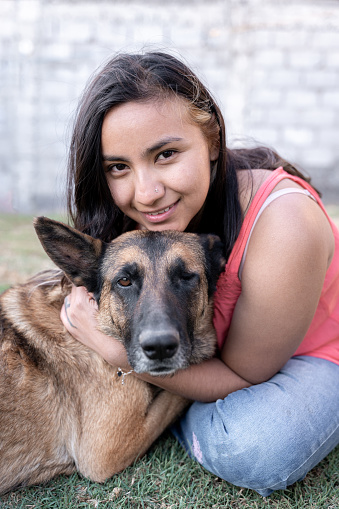 Portrait of a young Hispanic woman hugging her one-eyed dog in the garden. Concept of adopted pet love