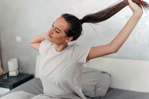 Woman in bed getting ready for the day with a simple hair tie